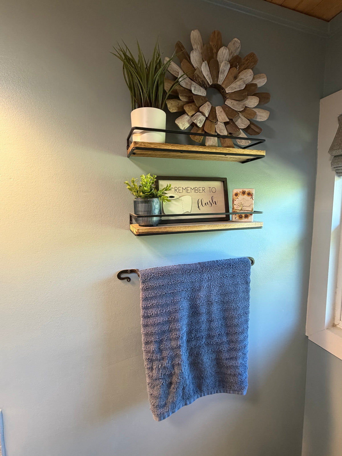Floating bathroom shelves providing wall storage above towel rack in small guest bathroom