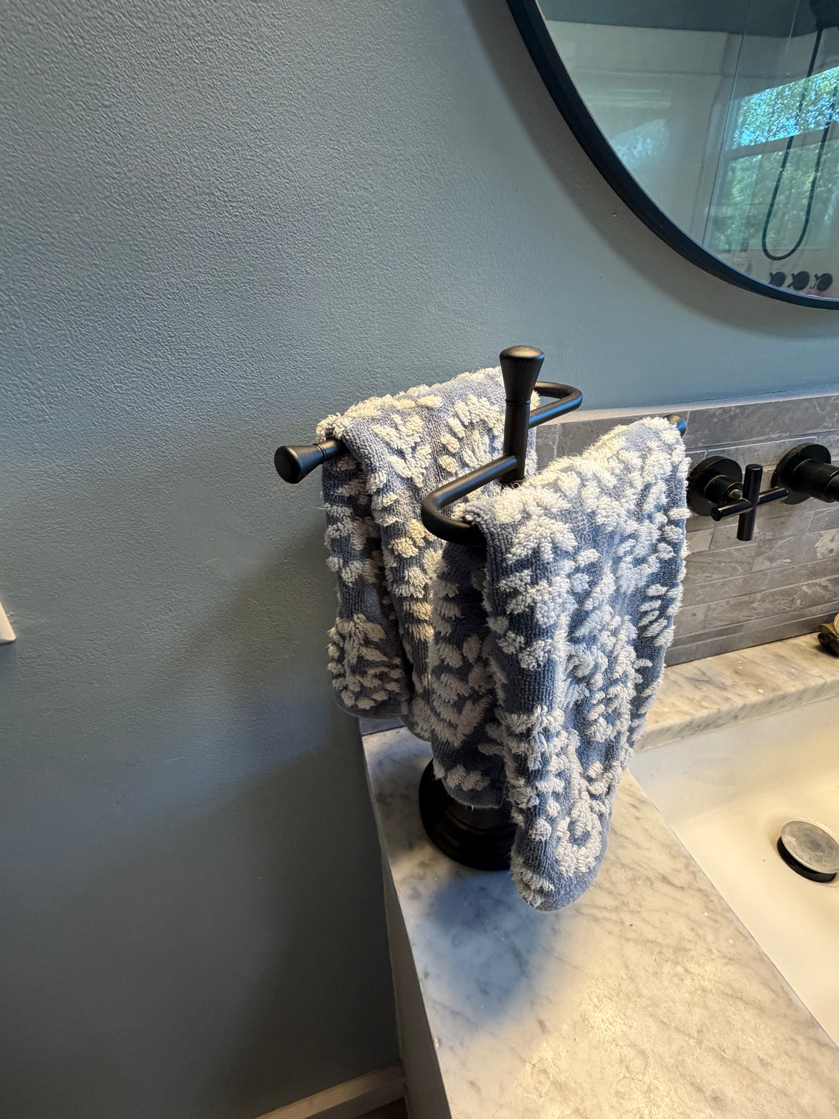 Black countertop hand towel stand on narrow vanity in Better Within guest bathroom