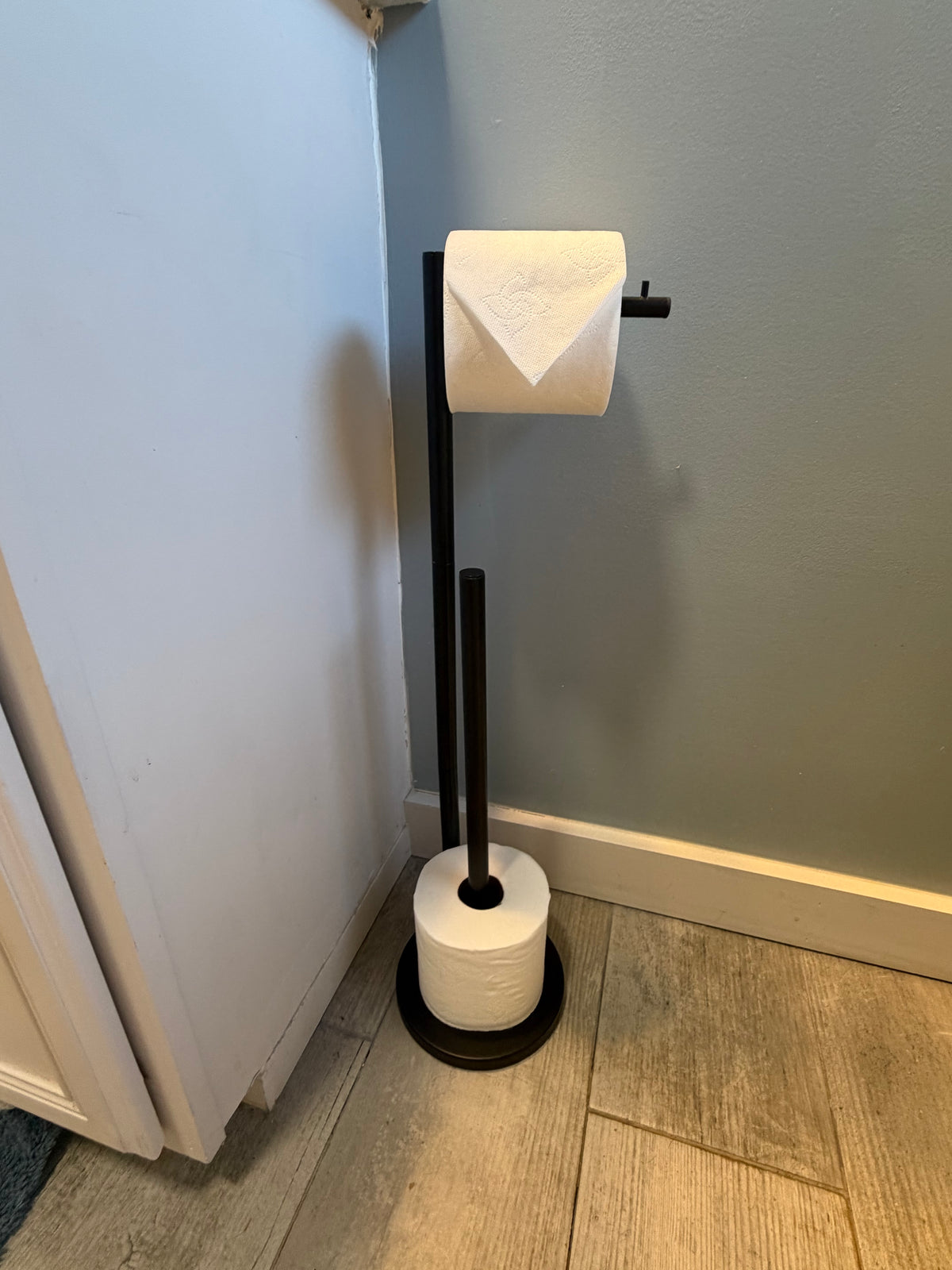 Black freestanding toilet paper holder with extra roll storage in Better Within guest bathroom